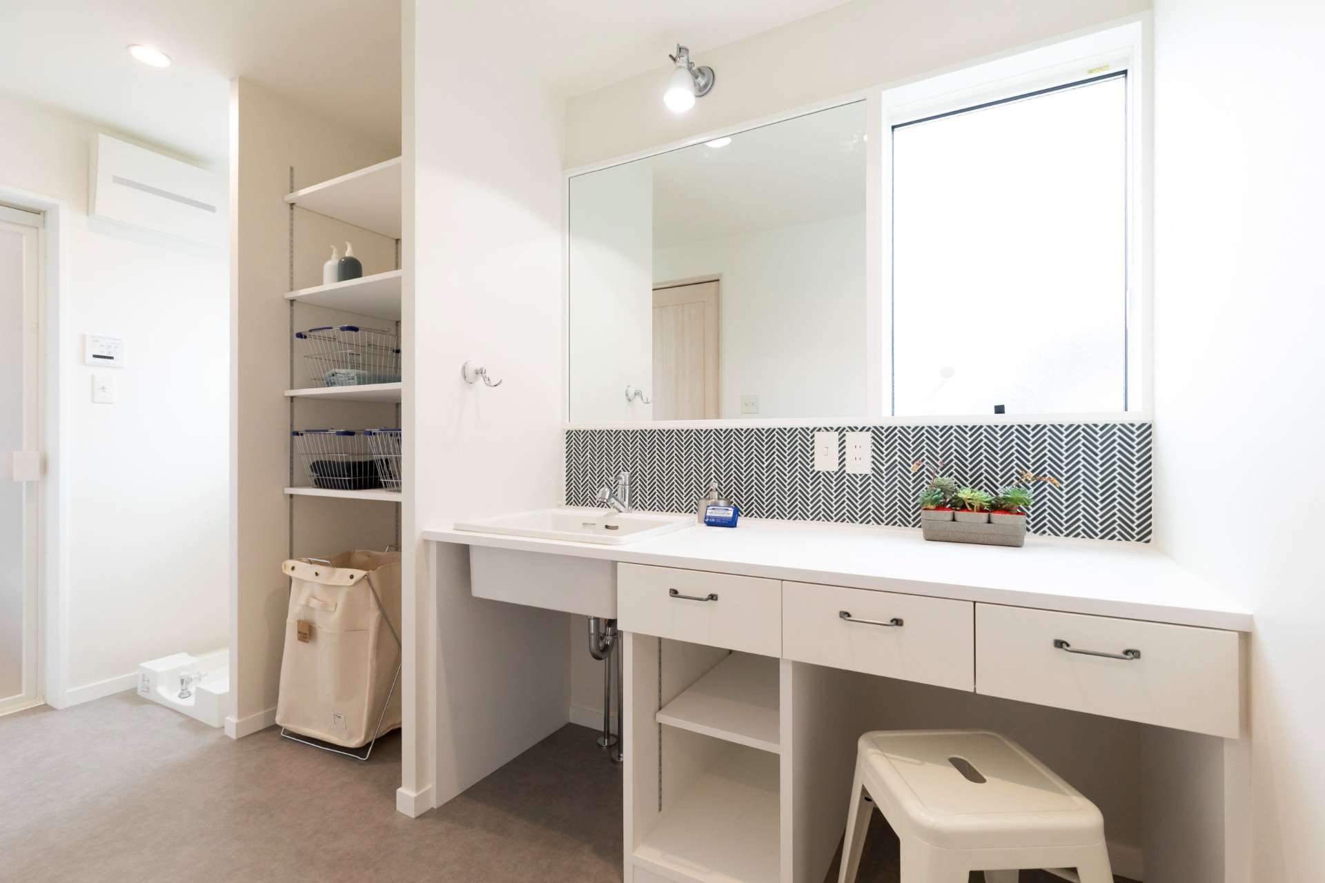 【1F　洗面】<br>清潔感の溢れる洗面はオリジナル造作。<br>ホワイトに統一された空間に、ネイビーのヘリンボーン貼りタイルが良く映える空間となった。